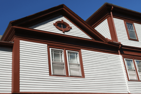 A clean, sturdy GRT Roofing home shows strong siding and windows under a clear blue sky.